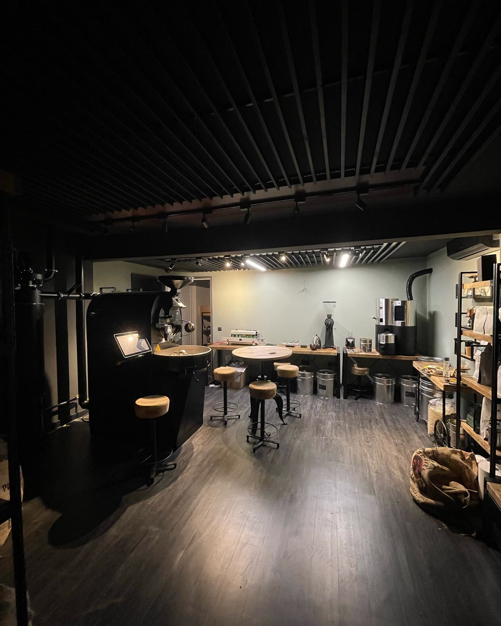 The current Duca Coffee Roasters roastery, with the roaster, green coffee sacks, and tasting bar