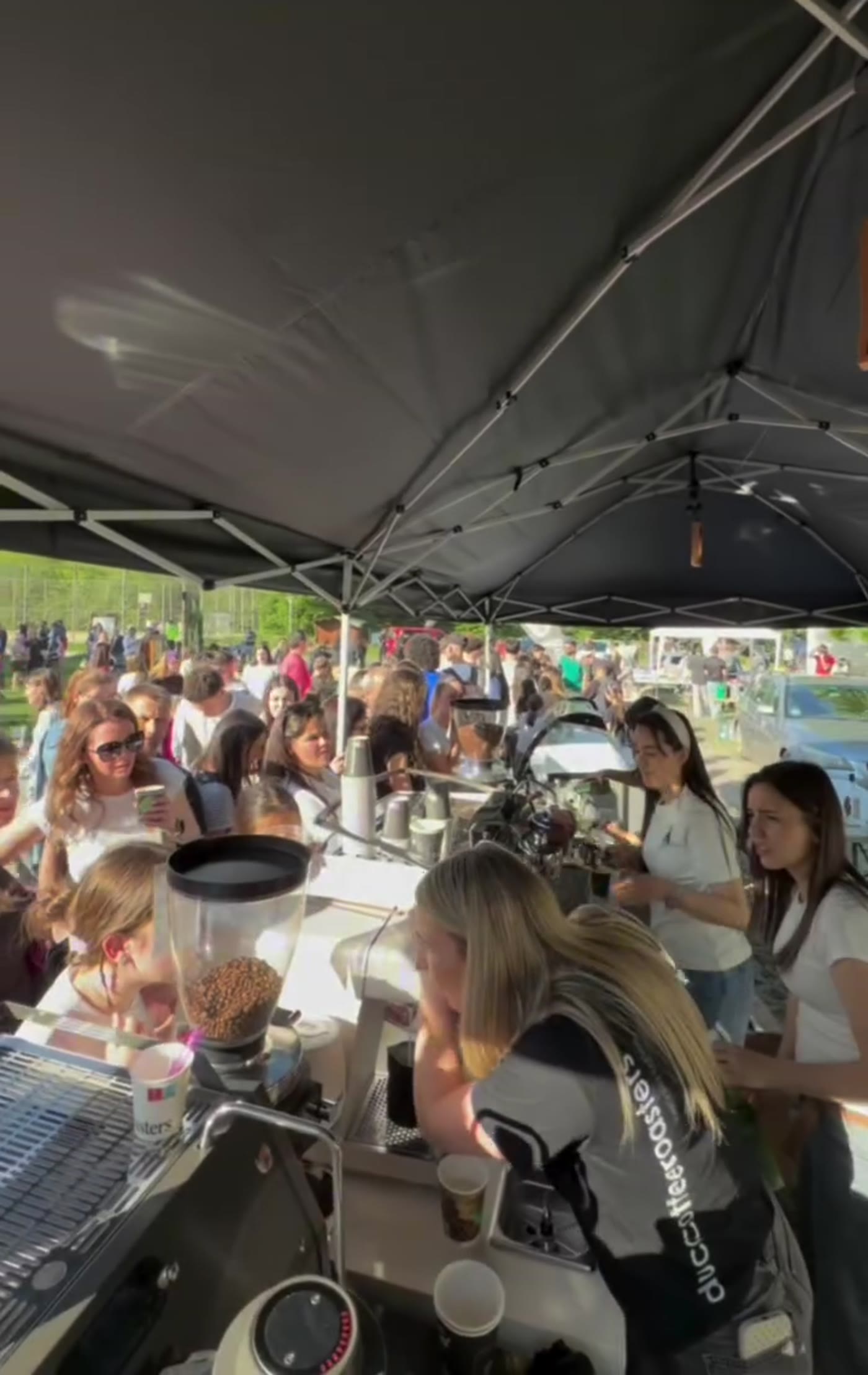 A crowd being served at Duca Coffee Roasters' mobile coffee bar at an outdoor event