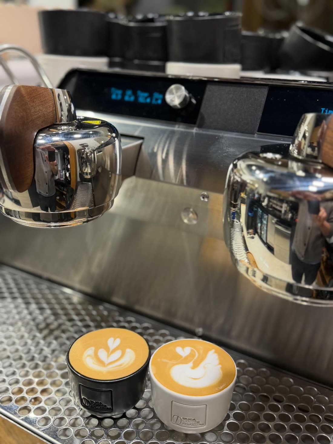 Two espresso drinks with latte art under the machine's group heads