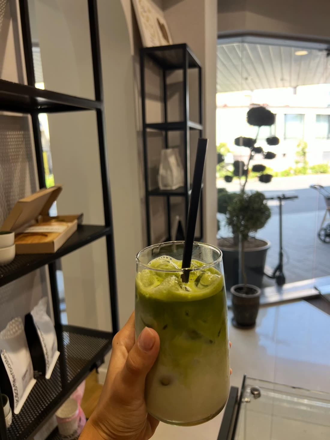 A hand holding an iced drink inside the shop