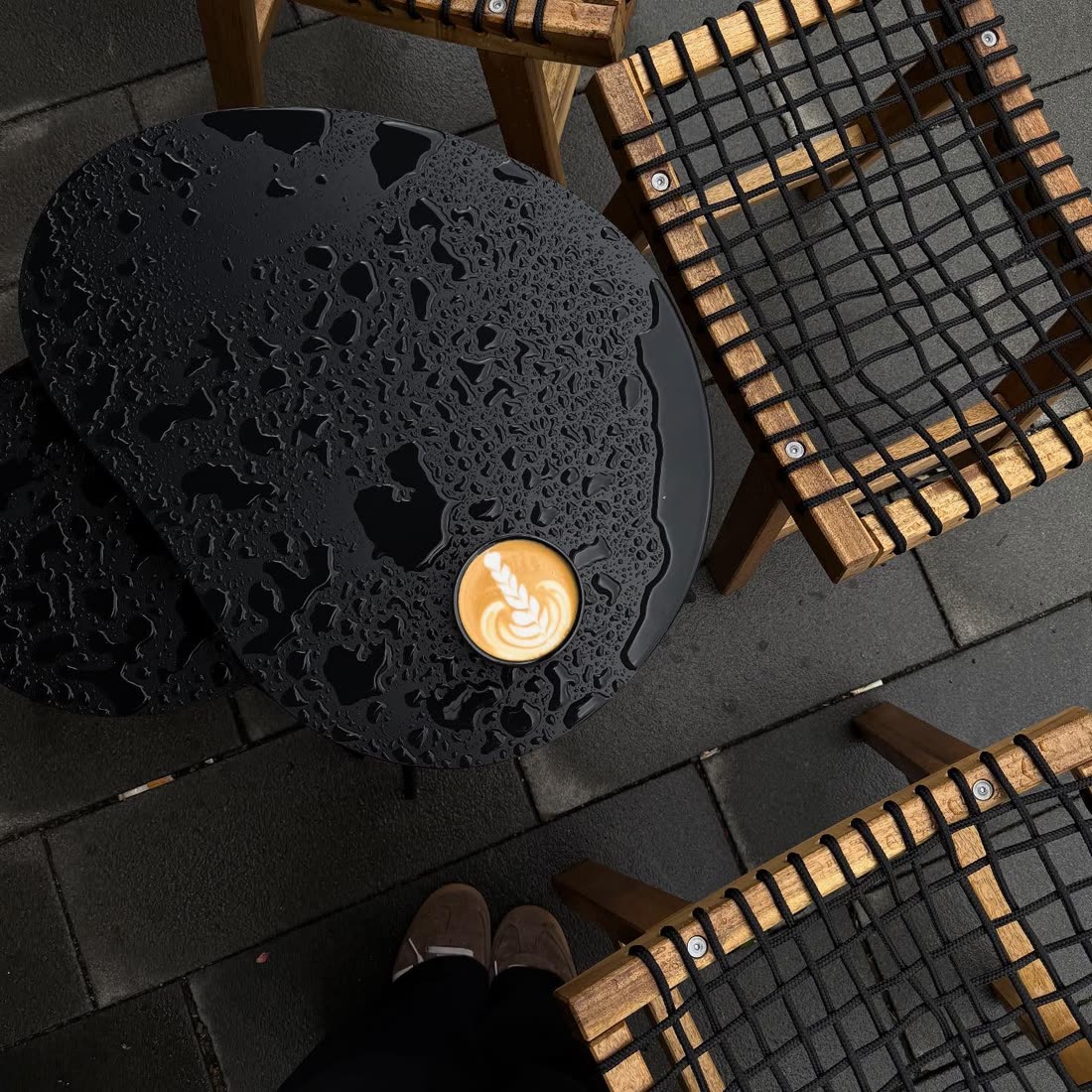 Overhead view of a latte on a rain-speckled outdoor table