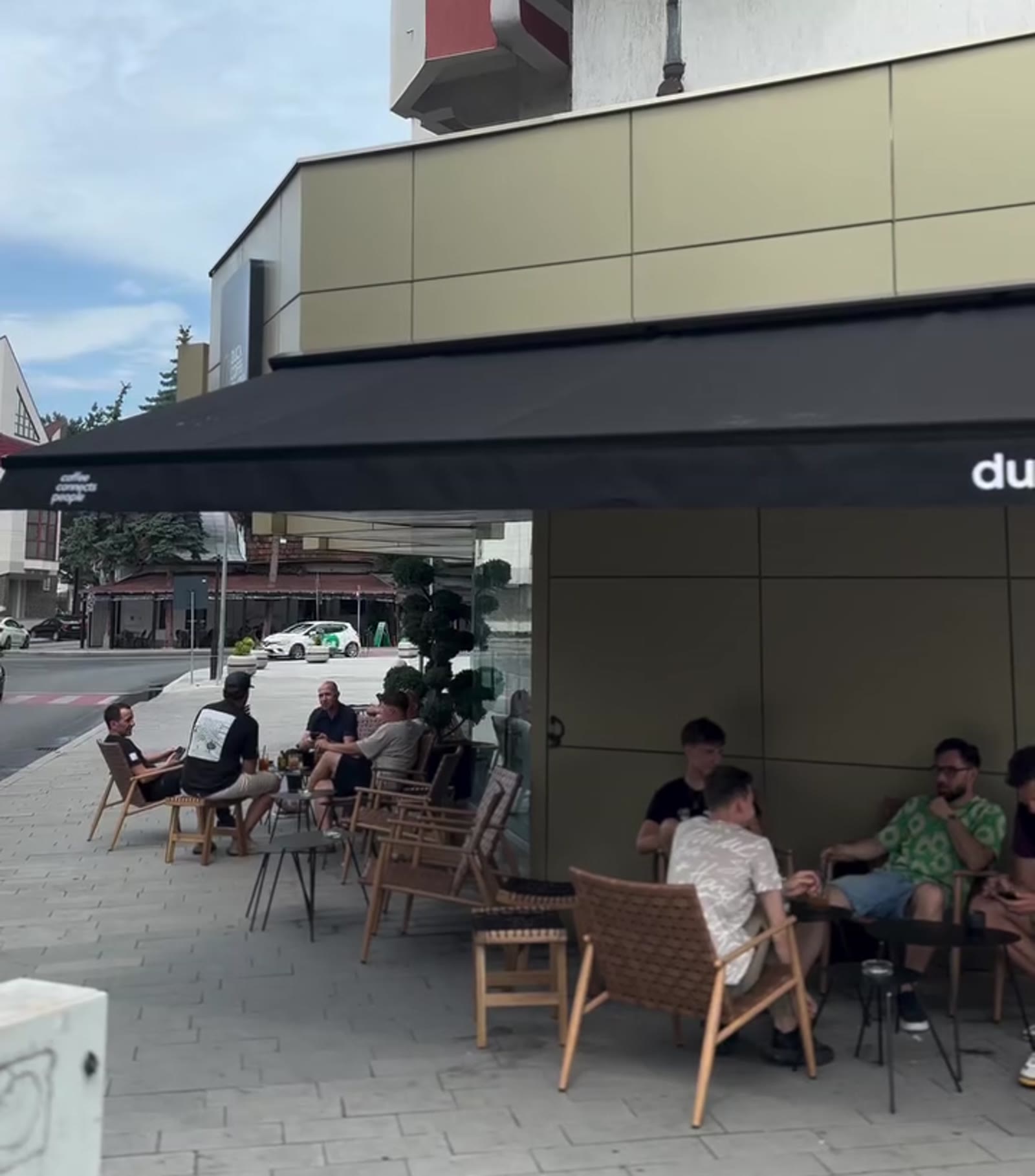 The Duca Coffee Roasters storefront, full of customers on a sunny day